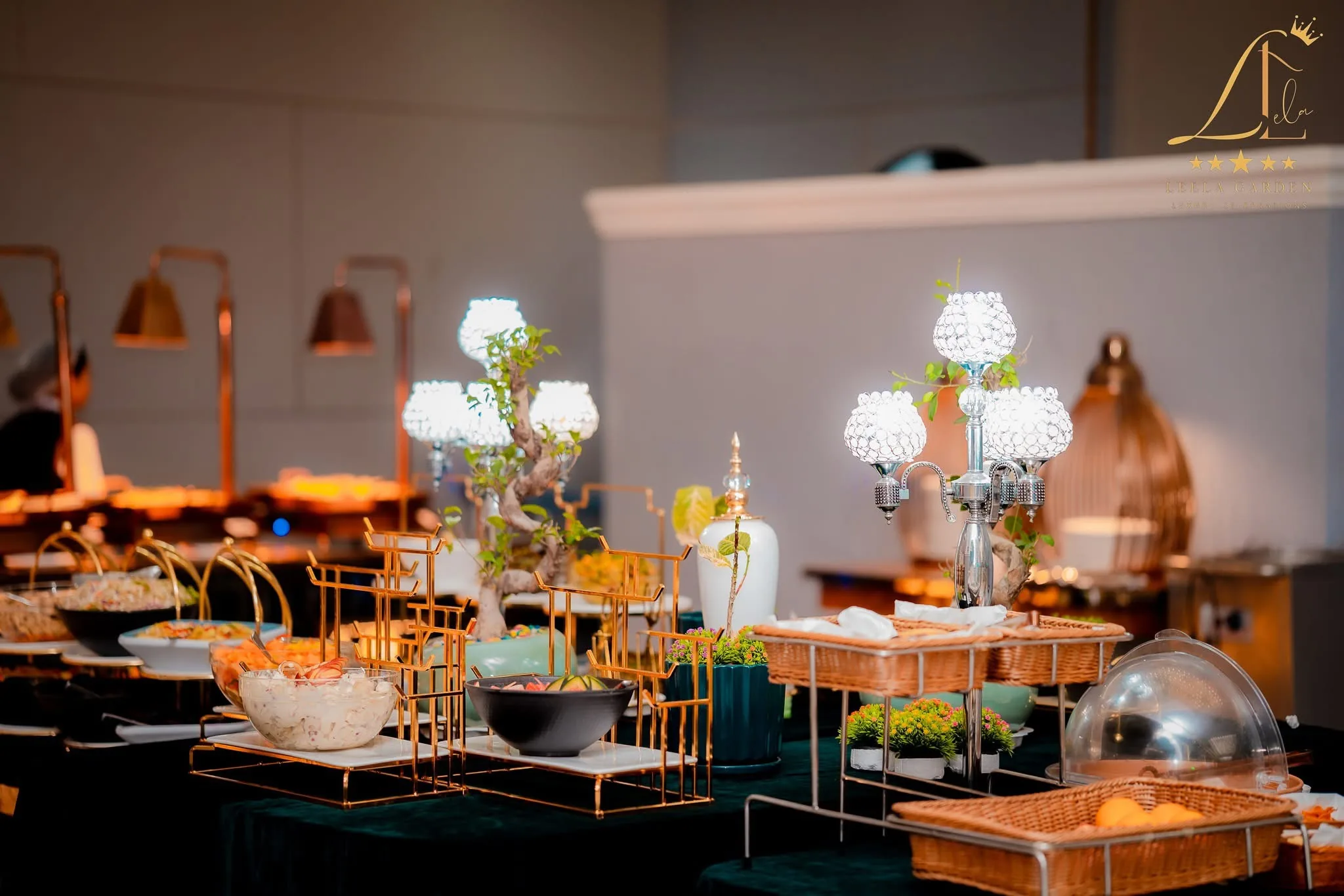 A detail of the buffet: crystal candelabra and brass lamps above canapés arranged on deep teal linen.